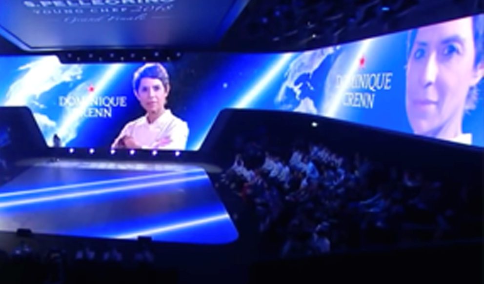 Panoramica del palcoscenico con presentazione di una cuoca per la San Pellegrino Young Chef del 2018